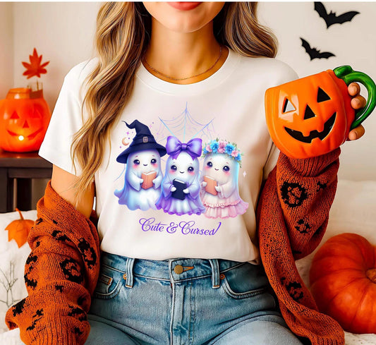 White cotton t-shirt with a centered graphic print. The illustration features three kawaii-style mice: on the left, a gray mouse wearing a black witch hat and holding an orange pumpkin; in the middle, a white mouse with a large pink bow; on the right, a brown mouse with an autumn floral crown. The design uses soft, pastel colors, creating a cheerful and whimsical Halloween vibe.